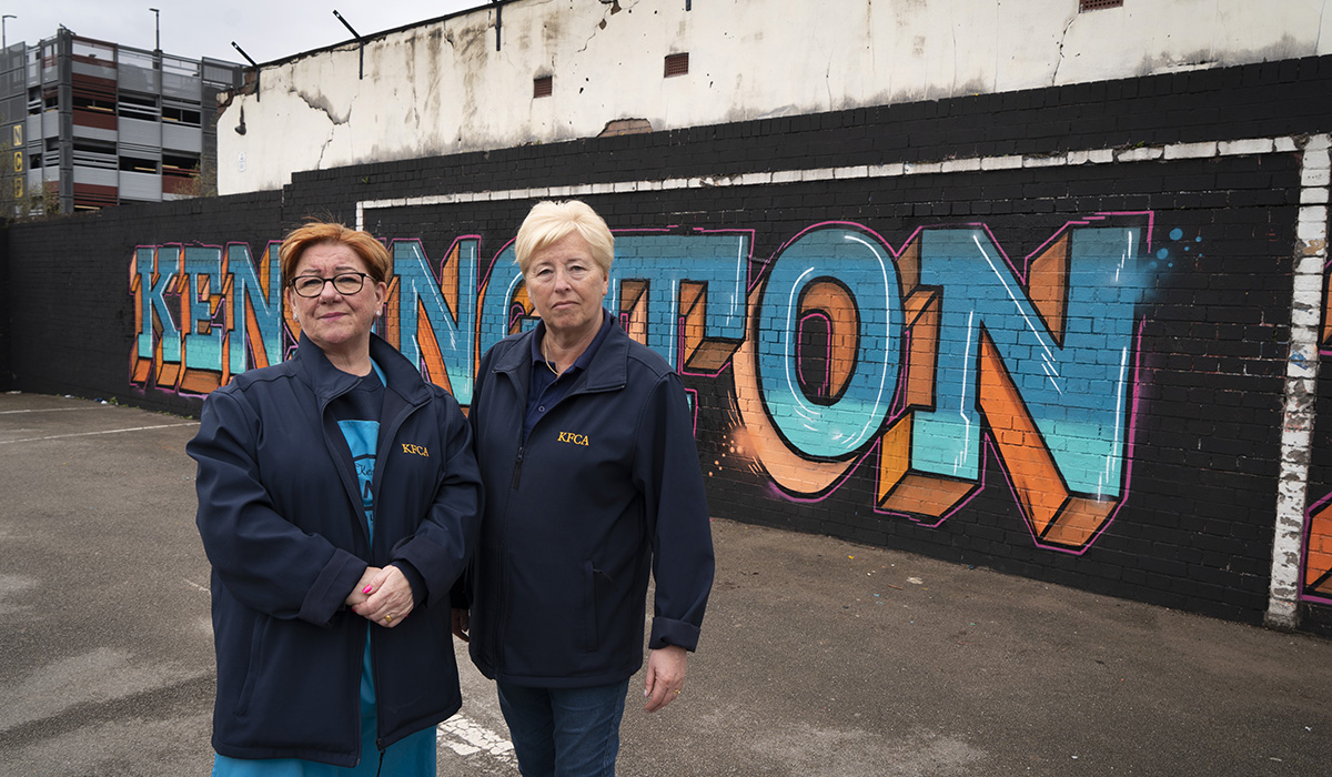 Myra and Sue in front of the 'Kensington' mural outside the Kensington Fields community centre