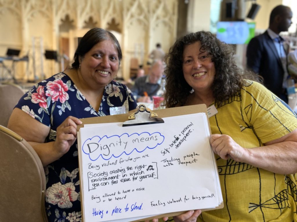 Rahela Khan and Jayne Gosnall hold a board with "Dignity means...." on it.