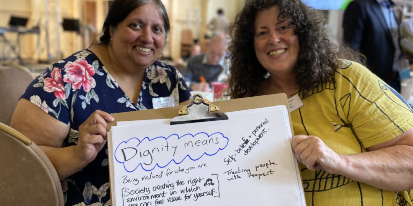Rahela Khan and Jayne Gosnall hold a board with "Dignity means...." on it.