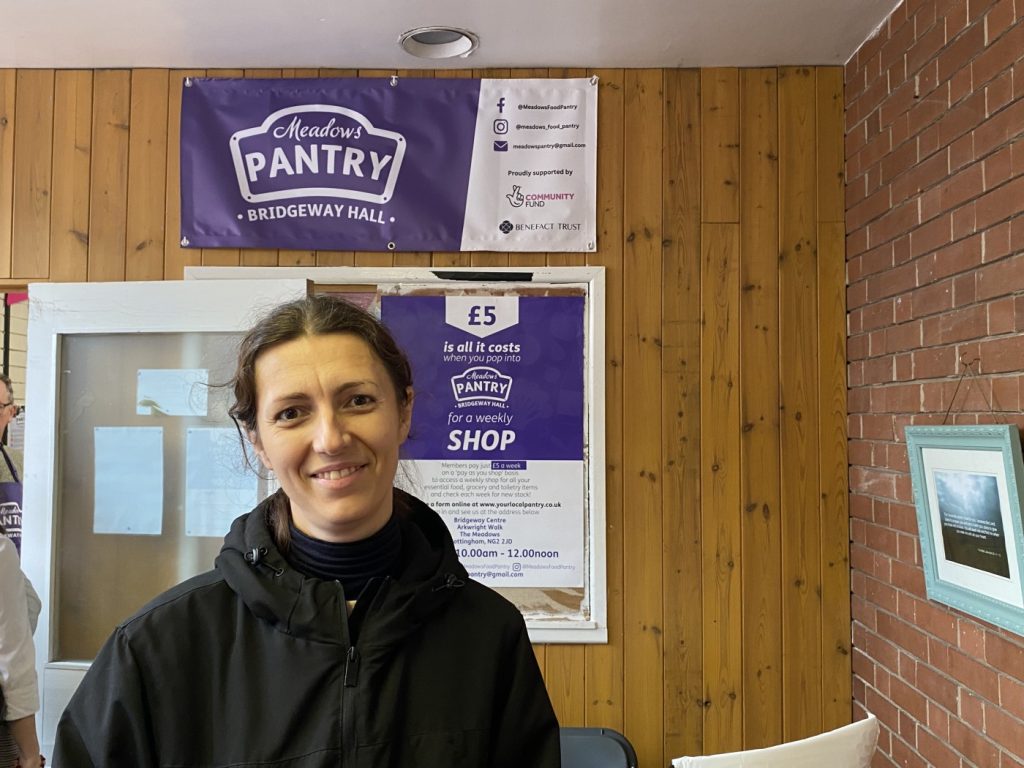 A woman in a black coat in front of a Meadows Pantry banner