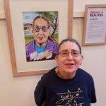 Susan stands in front of her portrait, smiling