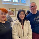 Liudmyla, Rebecca and Stephen stand in front of the portraits, as other people view the pictures