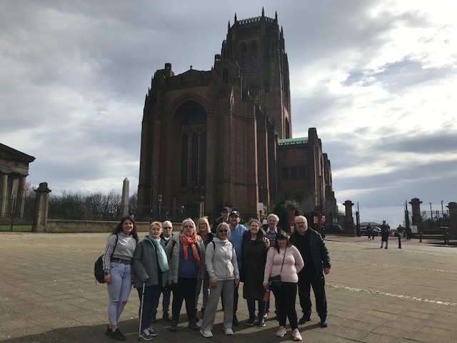 About 12 people in a group, with Liverpool Anglican Cathedral in the background