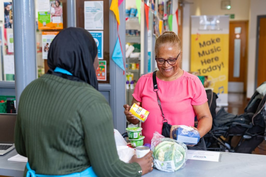 A Pantry member in a pink top takes her groceries to the counter.