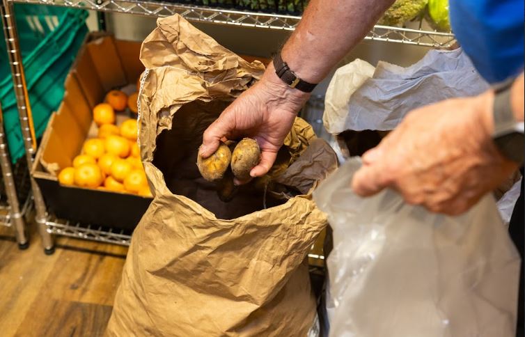 A volunteer taking potatoes from a sack in a community pantry