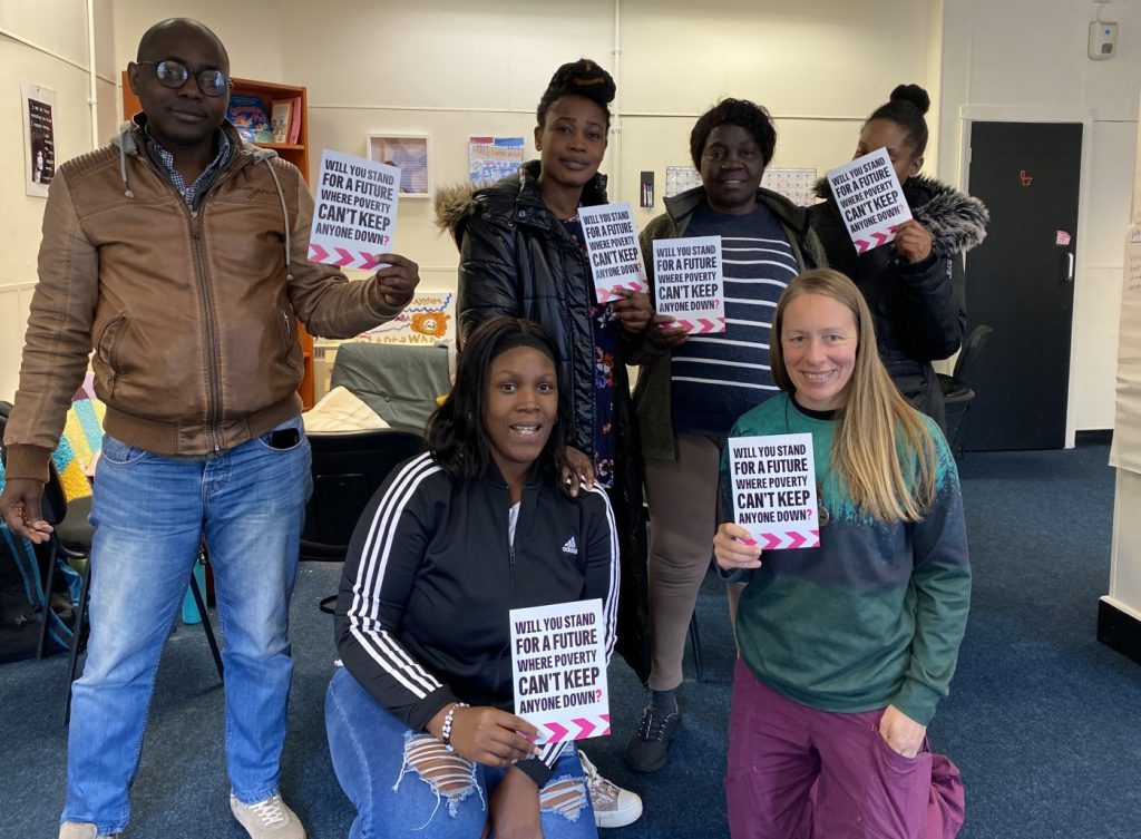 A group of 6 people, four standing and two crouching in front. They're holding Let's End Poverty postcards.