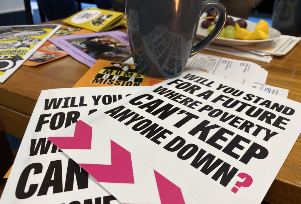 A Let's End Poverty postcard, with a mug alongside