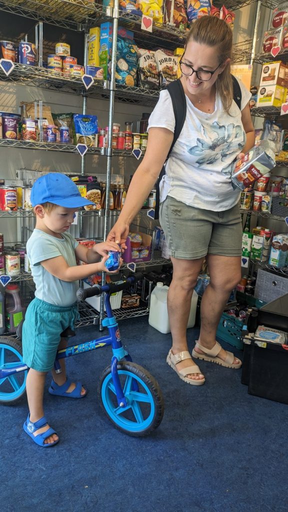 A young child with a small bike, and an adult in Broomhouse Pantry
