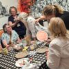 People sit around a table, as part of a plate-making art project