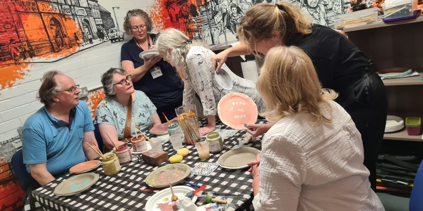 People sit around a table, as part of a plate-making art project