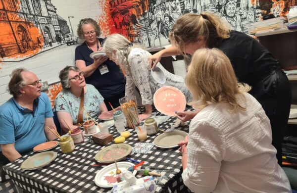 People sit around a table, as part of a plate-making art project