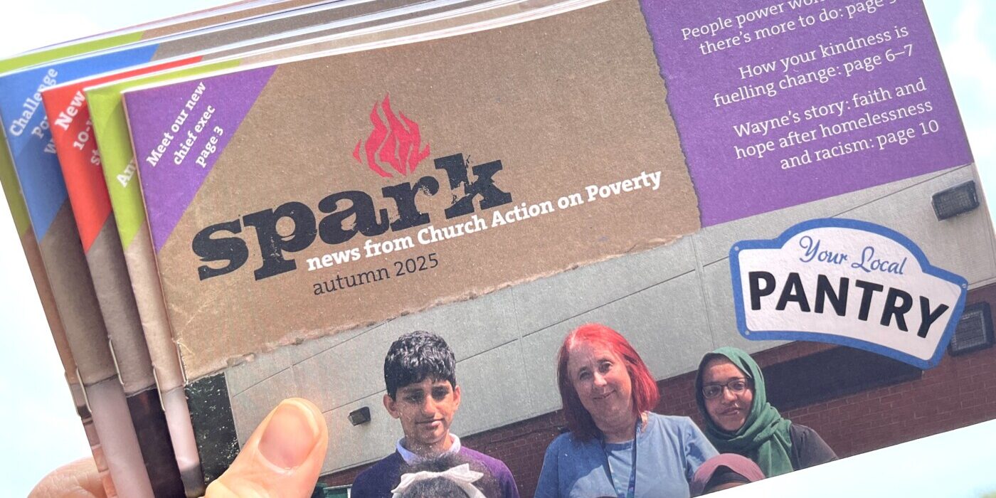 A hand holding a bundle of Spark newsletters