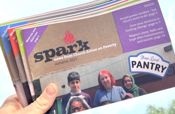 A hand holding a bundle of Spark newsletters