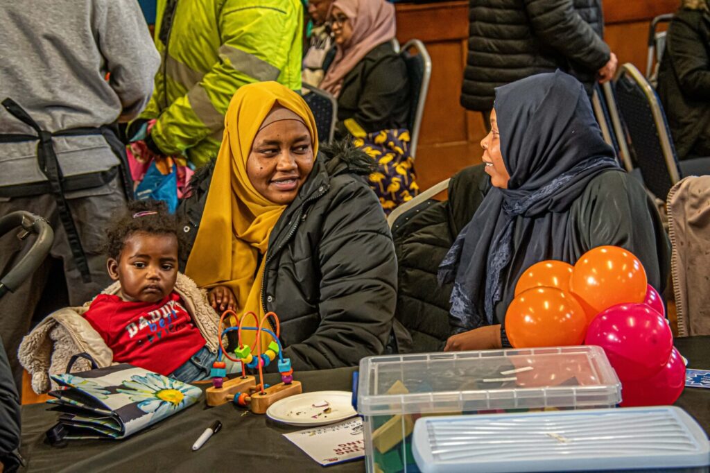 Two women and a toddler sitting chatting at a table