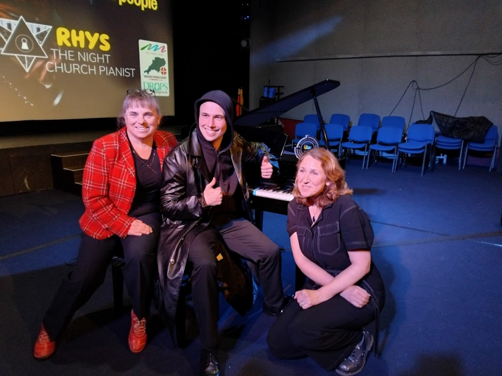 A posed shot of three people sitting in a hall