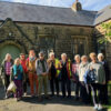 A group of 11 people standing in front of a church building
