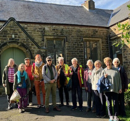 A group of 11 people standing in front of a church building