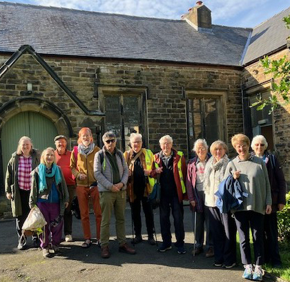 A group of 11 people standing in front of a church building